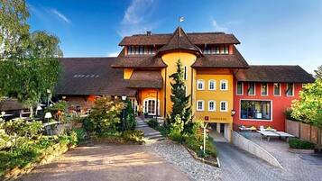 Ein traditionelles Gebäude mit einem zentralen Eingang, einer überdachten Außenbestuhlung und einer Flagge auf dem Dach.