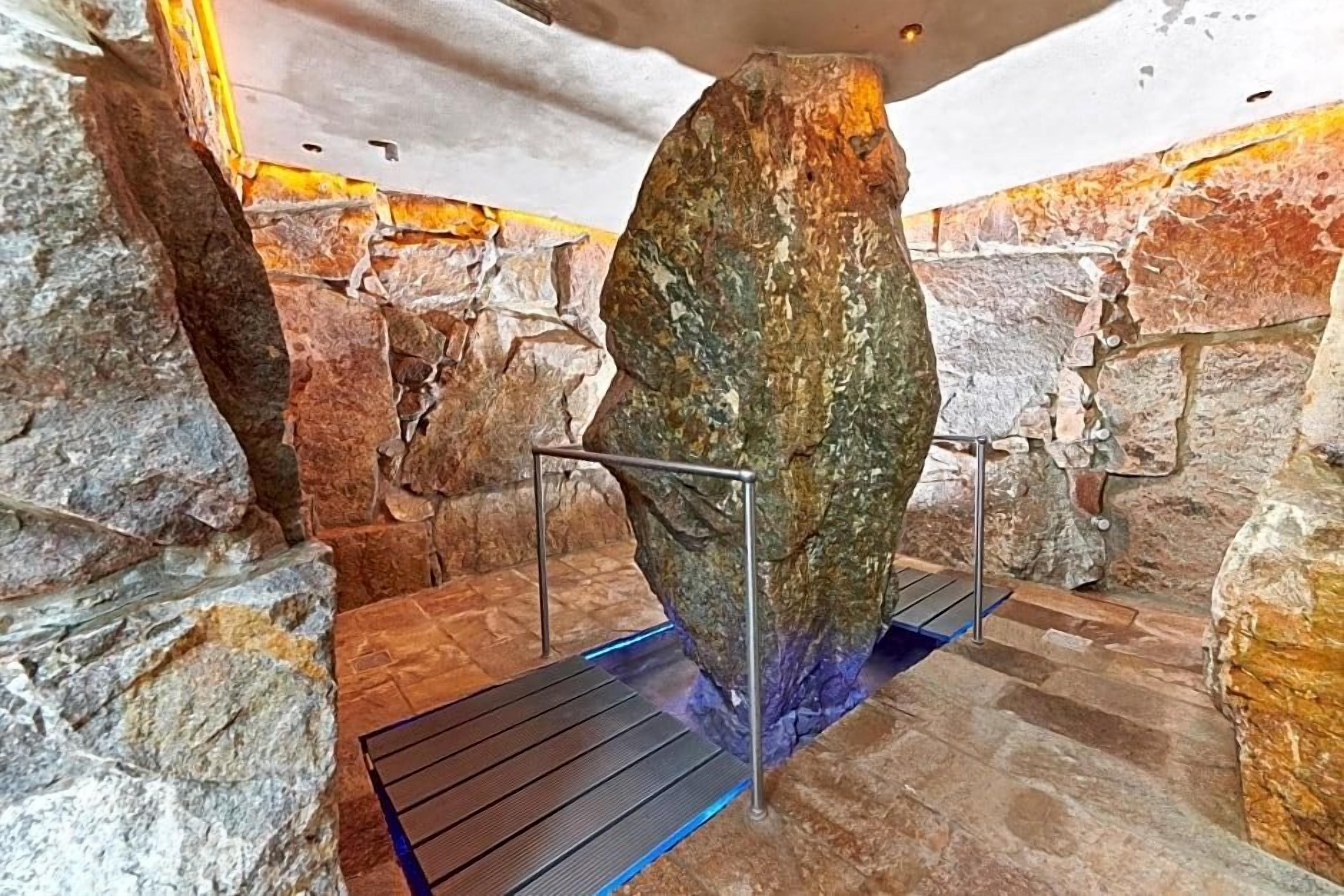 Ein Steingewölbe mit Metallgeländer und einer blau beleuchteten Plattform.