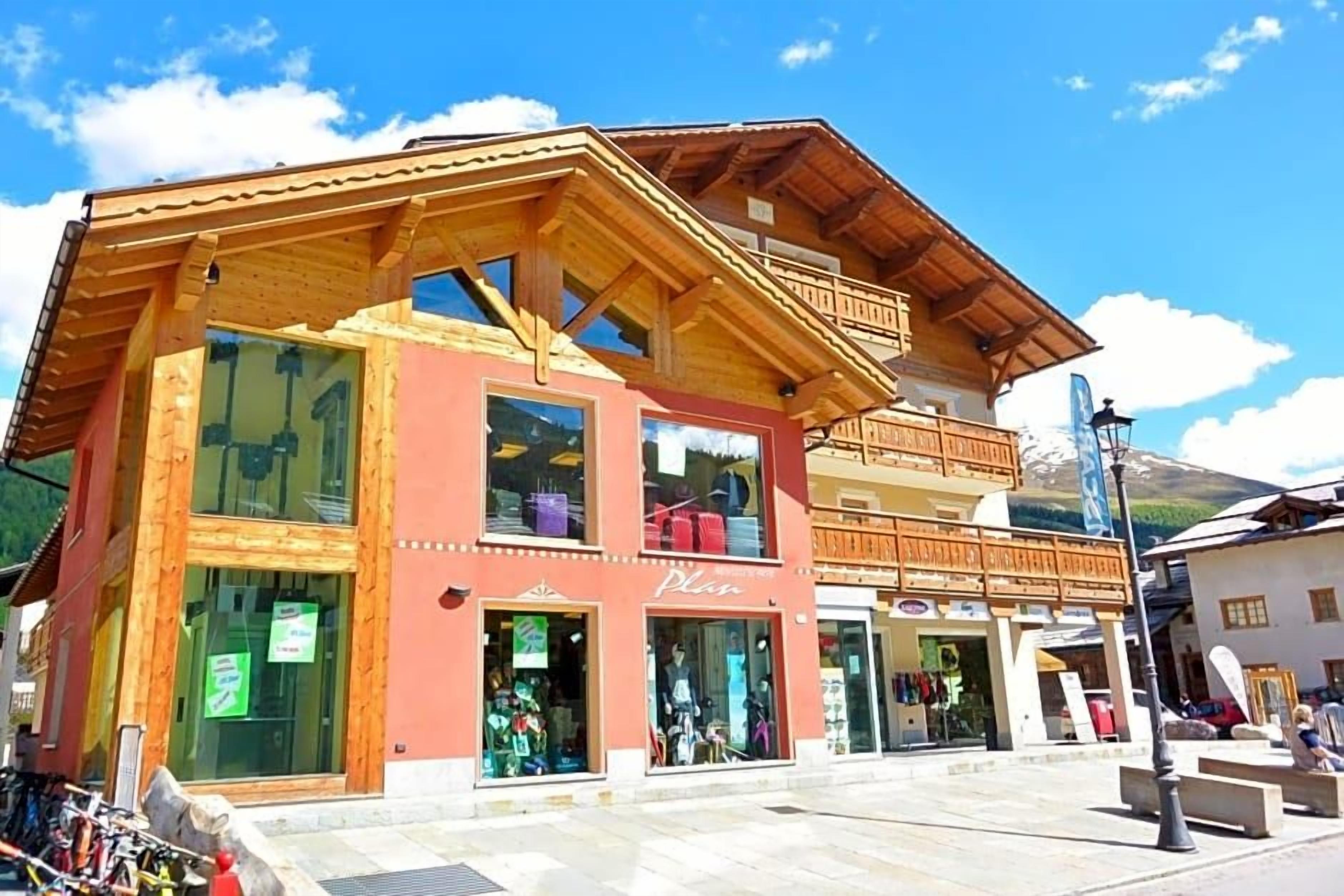 A wooden building with multiple storefronts, including a visible sign that says 'Plan'.