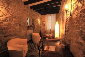 Une pièce chaleureuse avec des murs en pierre, une table en bois et deux fauteuils.