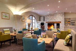 Um saguão de hotel com áreas de estar, lareira e obras de arte nas paredes.