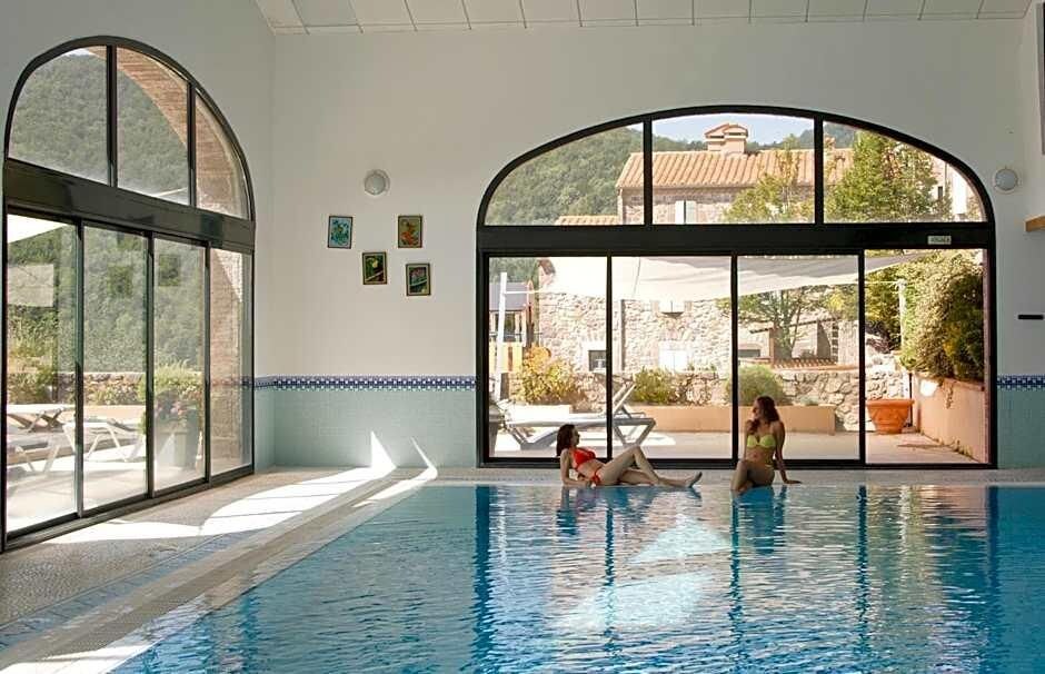 An indoor swimming pool with clear glass walls, a tiled floor, and a view of the outside.