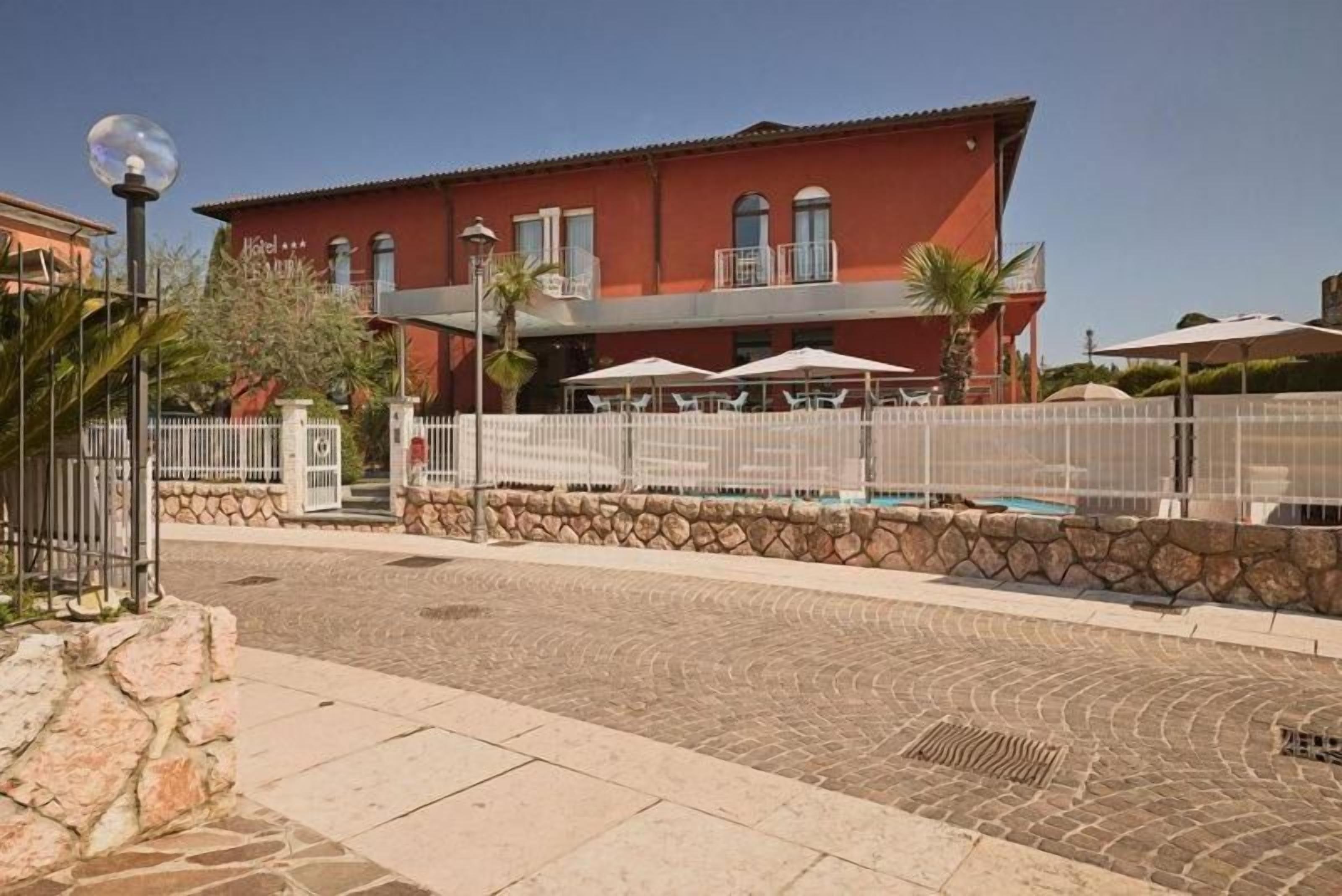 Un hôtel à la façade rouge, doté d’une terrasse et d’une piscine.