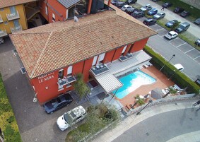 Ein Hotel mit Schwimmbad, mehreren Balkonen und einem Parkplatz.