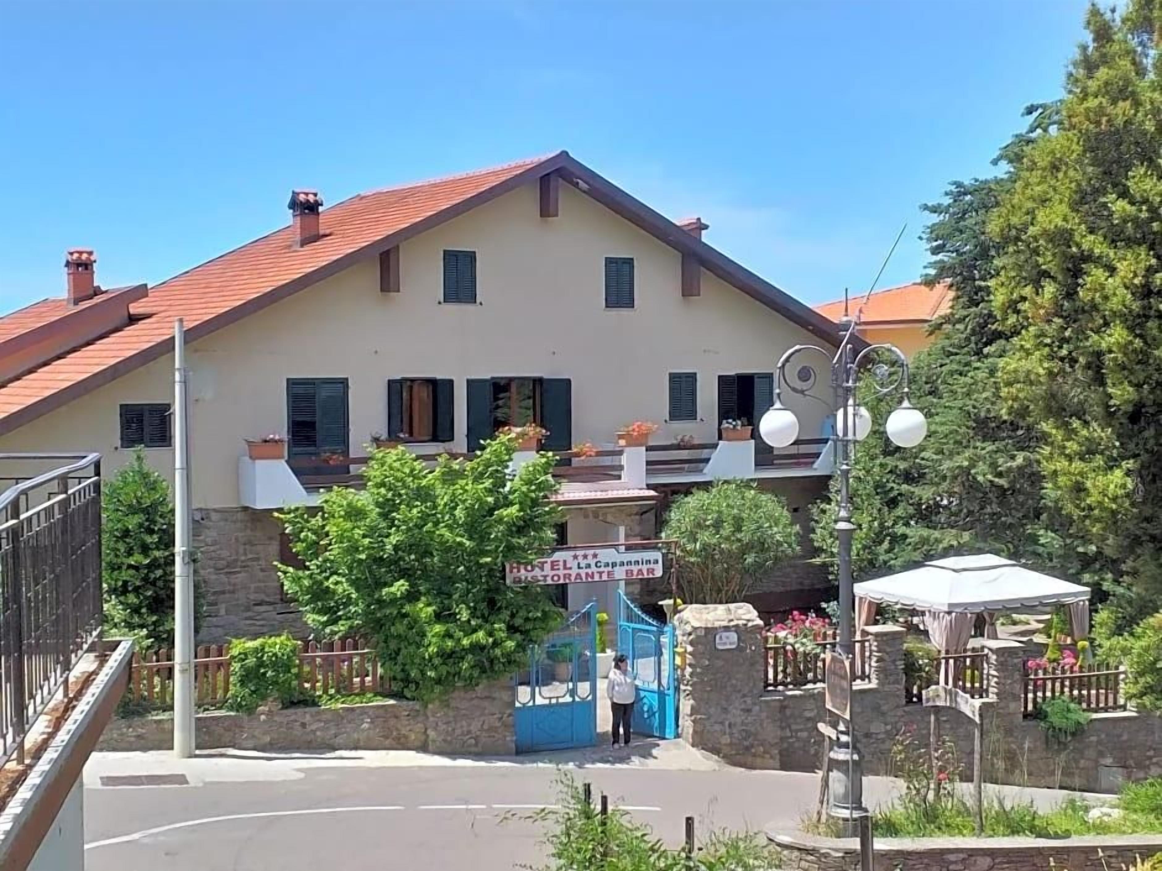 Un hotel con tetto in tegole rosse, insegna per ristorante e bar e cancello blu.