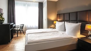Ein Hotelzimmer mit einem großen Bett, Nachttischlampen, einem Schreibtisch und einem Sessel.