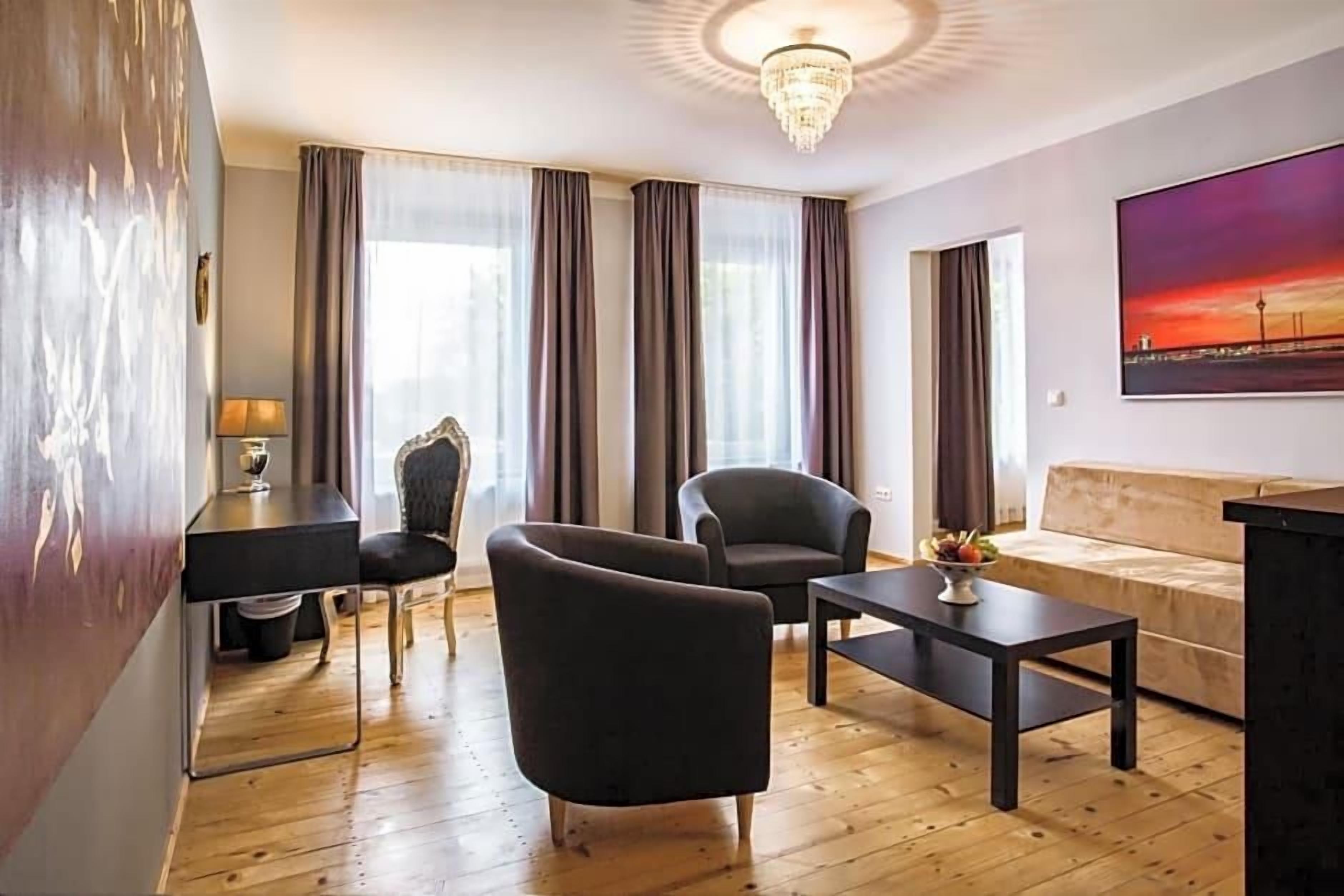 Ein modernes Wohnzimmer mit einer Couch, zwei Sesseln, einem Couchtisch und einem Schreibtisch mit einer Lampe.