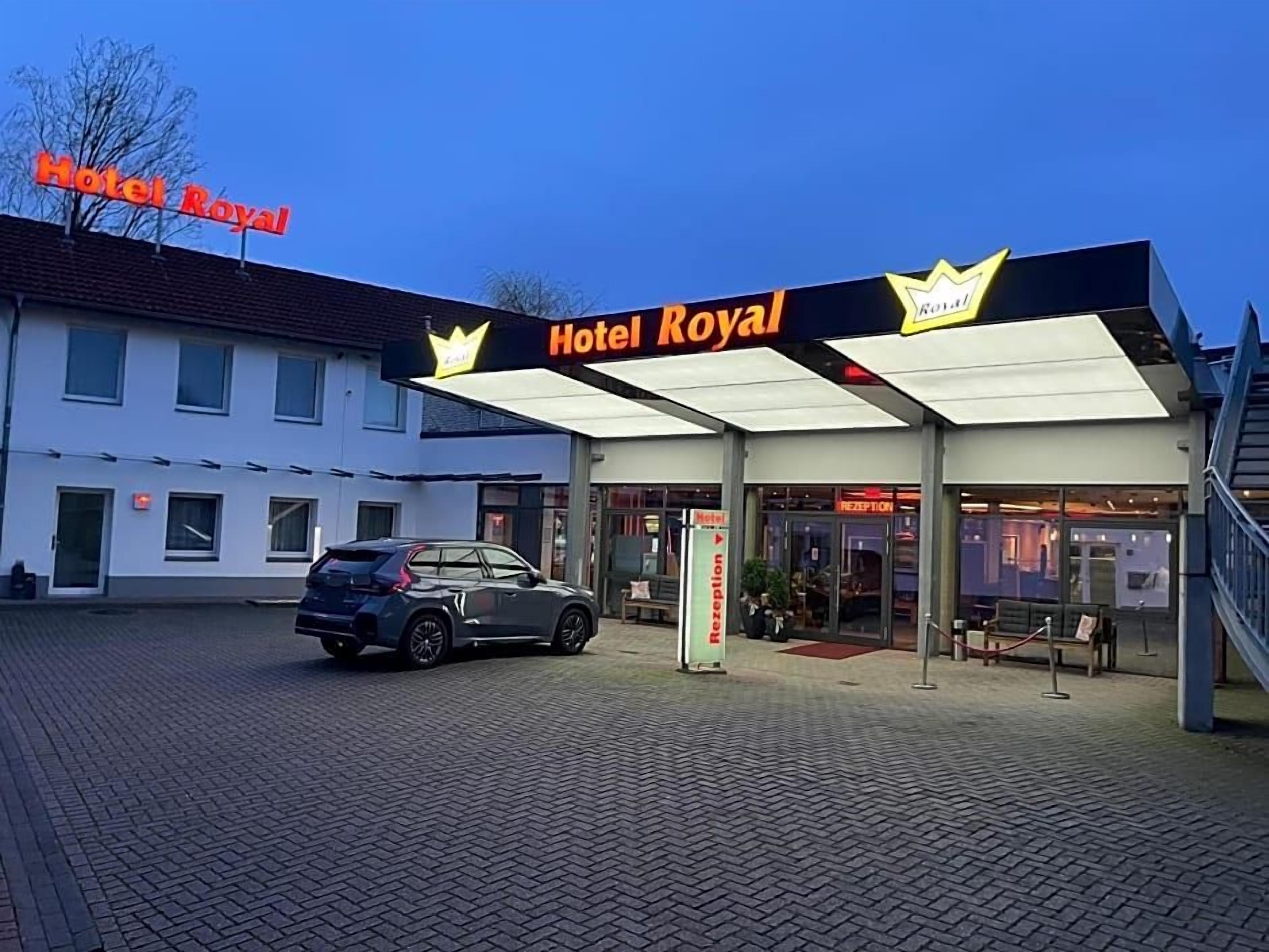 A hotel entrance with a sign reading 'Hotel Royal' and a reception desk.