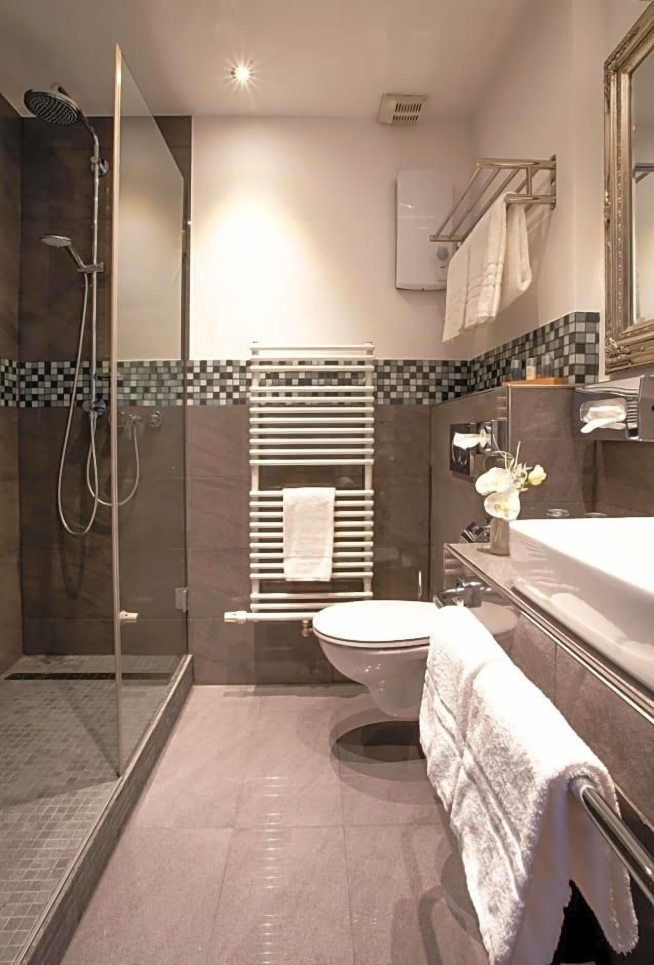 Ein modernes Badezimmer mit einer Duschkabine, einer Toilette und einem Waschtisch mit Spiegel.