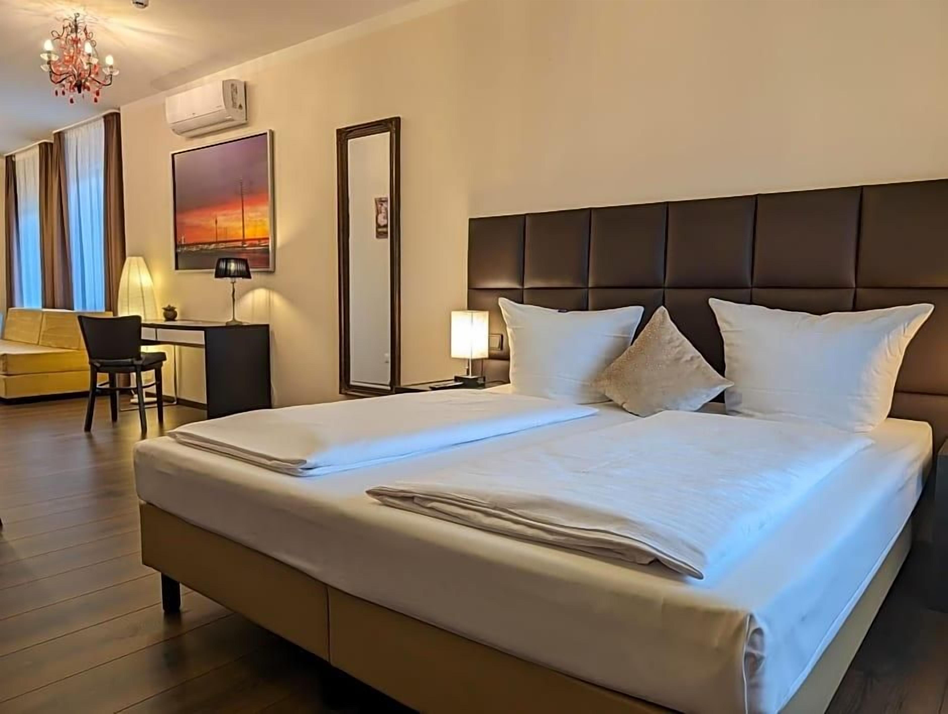 A hotel room with a large bed, a desk, and a chair.