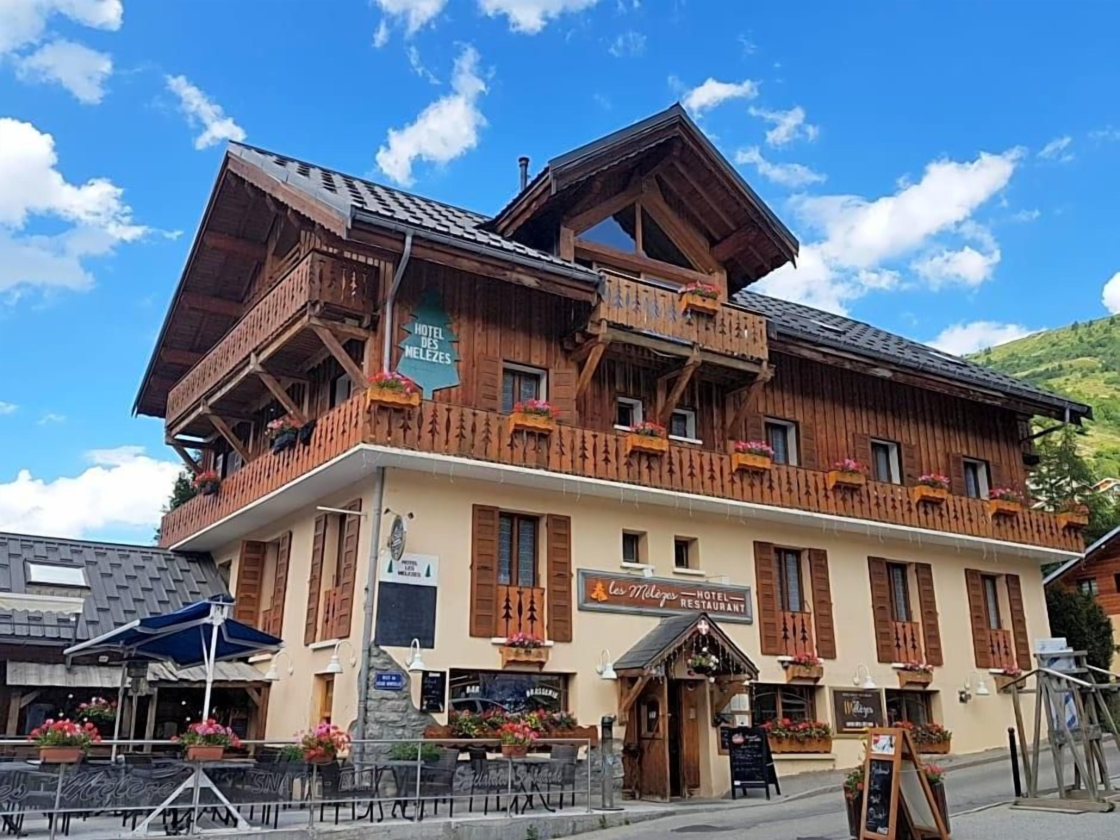 Un hôtel en bois doté de balcons, d’un restaurant et d’une terrasse.