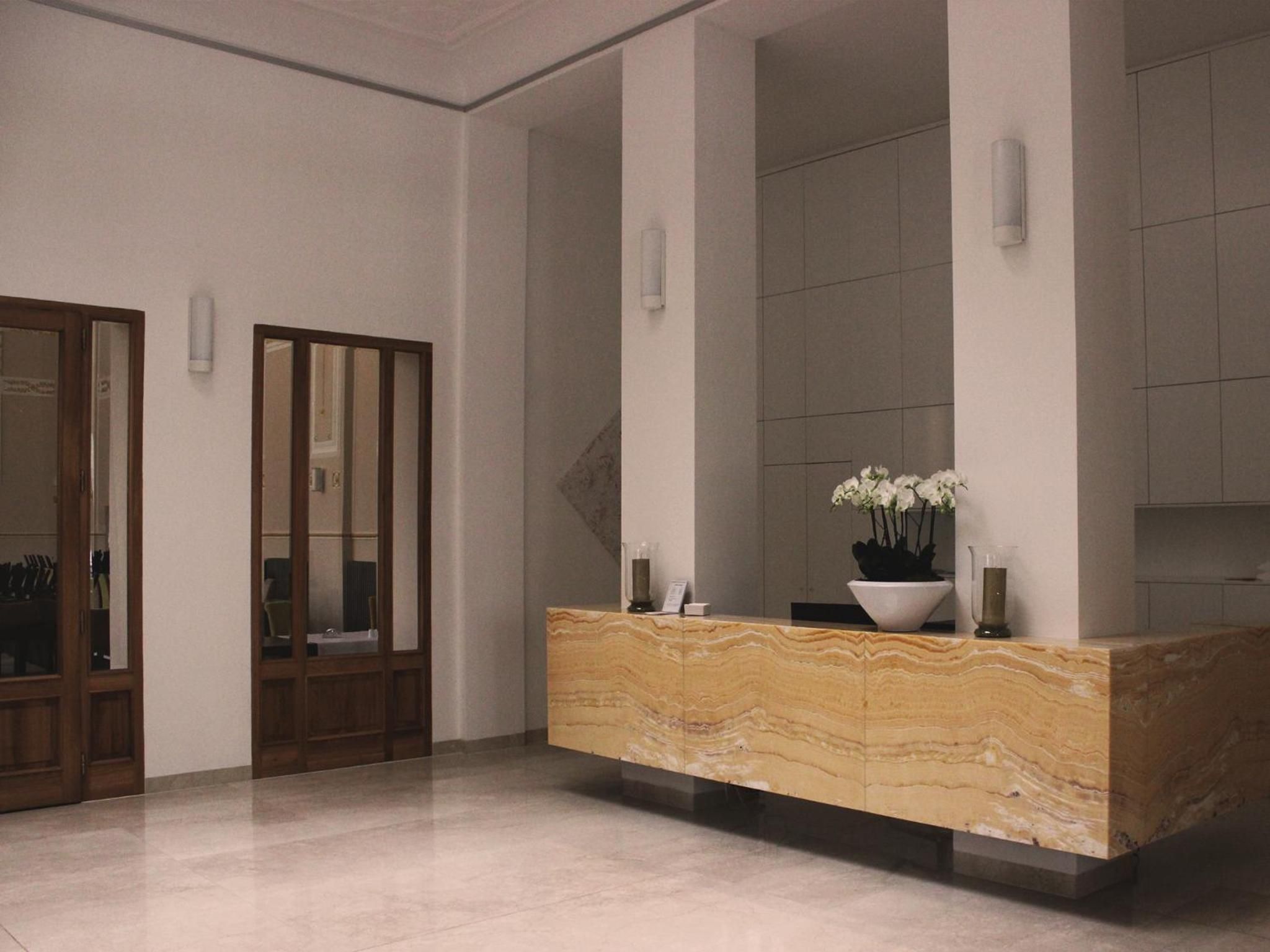 A reception area with a marble counter, a potted plant, and a door with a mirror.