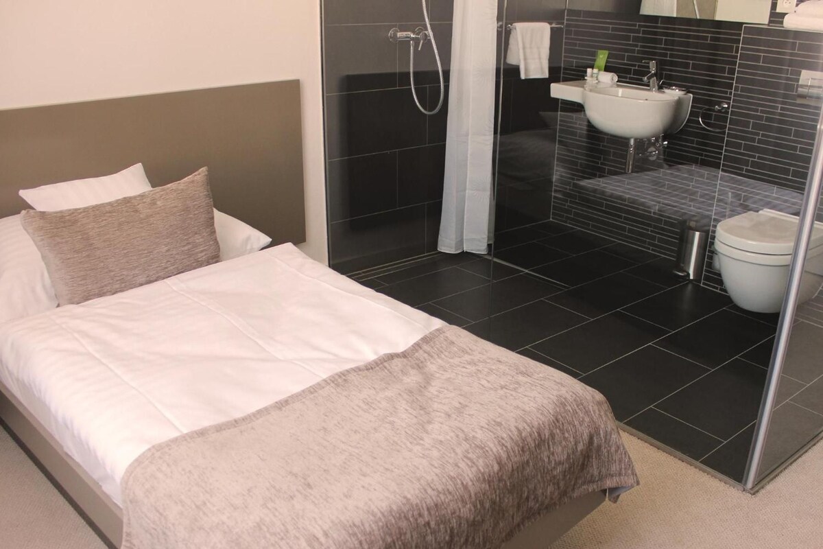 A hotel room with a bed, a shower, and a bathroom.