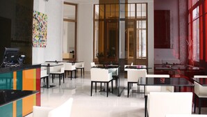 A modern hotel lobby with a reception desk, seating area, and large windows. - Hotel Lev (Levice)