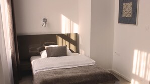 A bedroom with a bed, a wall-mounted light, and a framed picture. - Hotel Lev (Levice)