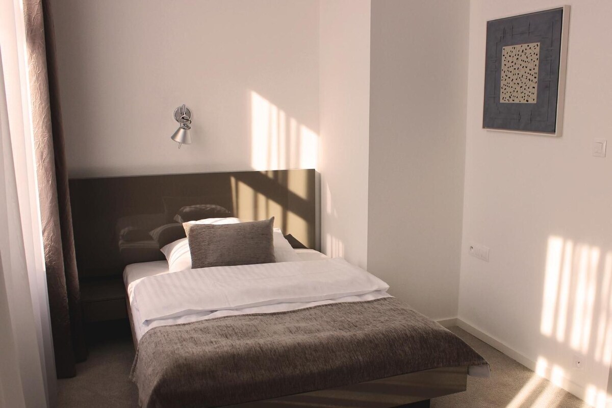Quarto com cama, luminária na parede e quadro emoldurado.