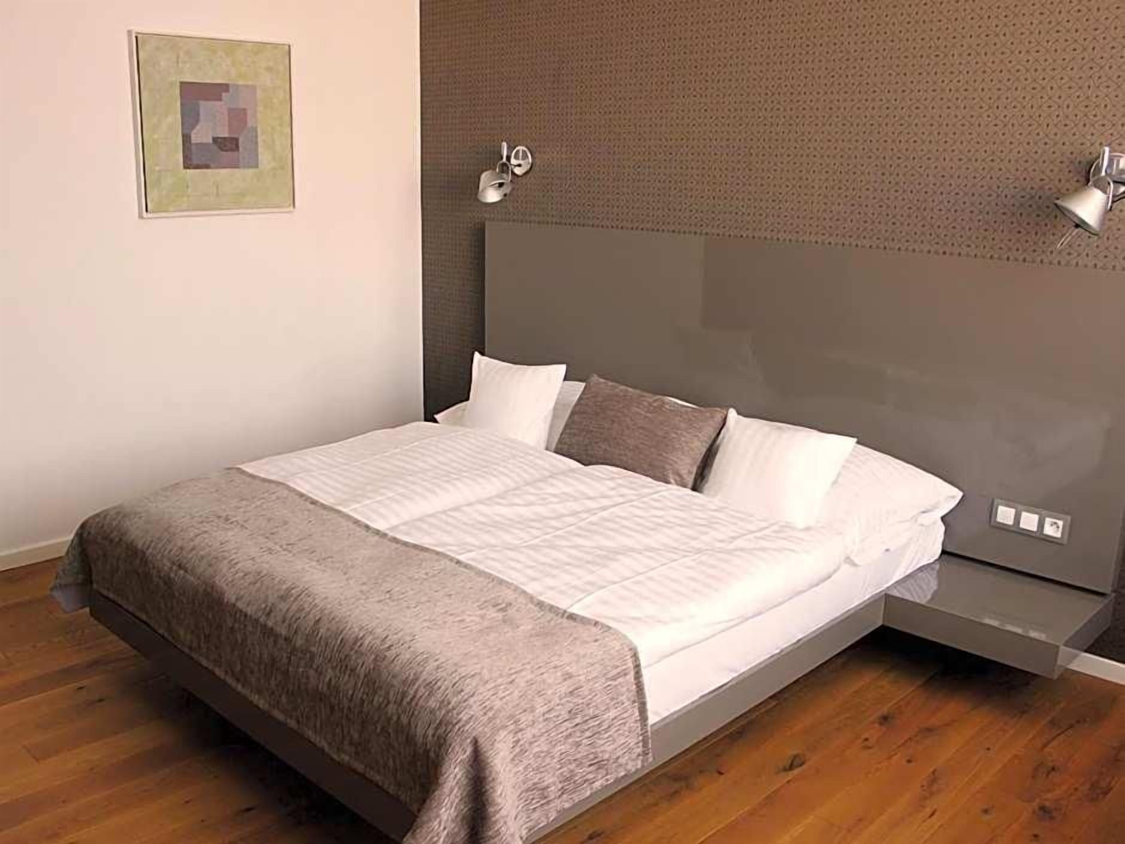 Une chambre à coucher moderne avec un lit, des tables de chevet et une lampe fixée au mur.