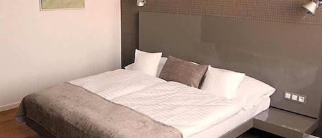 Une chambre à coucher moderne avec un lit, des tables de chevet et une lampe fixée au mur.