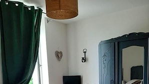 A bedroom with a bed, a desk, a chair, a wardrobe, and a hanging light fixture. - L Auberge Du Tire Bouchon (Couffé)