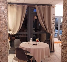Uma sala de jantar com uma mesa redonda, cadeiras e cortina.