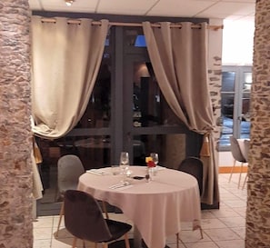 Uma sala de jantar com uma mesa redonda, cadeiras e cortina.