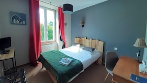 A hotel room with a bed, a desk, a chair, a television, and a window with curtains. - L Auberge Du Tire Bouchon (Couffé)