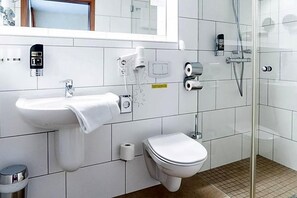 A modern bathroom with a toilet, sink, and shower. - Land Gut Hotel Am Ring (Meuspath)