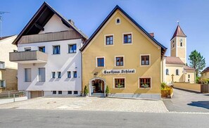 A building with a sign reading 'Gasthaus Schiesl' with a traditional European architectural style, a visible entrance, and a church tower in the background. - Gasthof Schiesl (Altendorf)