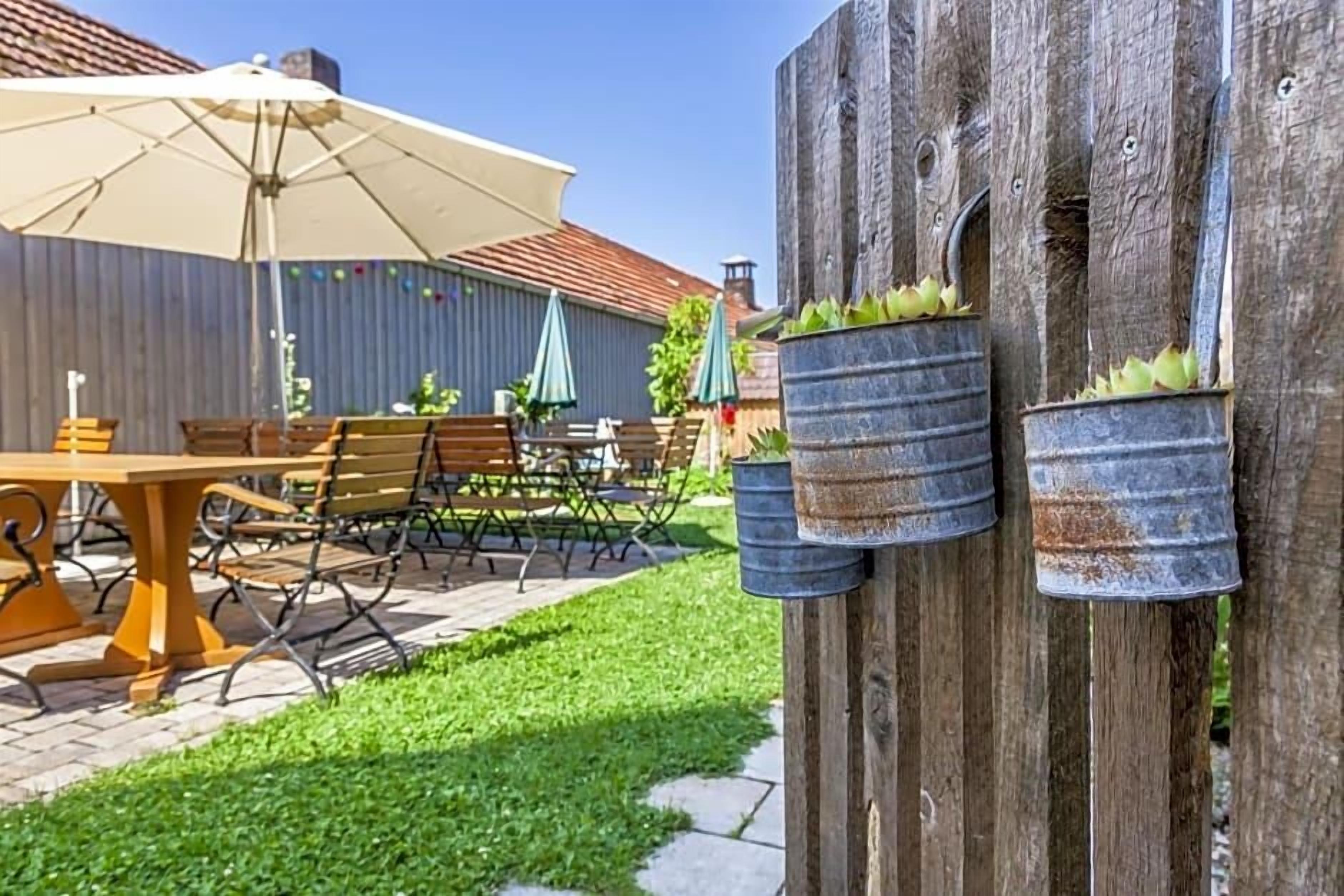Un patio con mobiliario exterior, cerca de madera y macetas con plantas verdes.