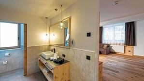 Ein modernes Badezimmer mit einem Holzwaschtisch, einem großen Spiegel und einem Fenster.