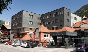 Un hotel con fachada moderna, varios balcones y un restaurante llamado 'Zum Mohren' al frente.