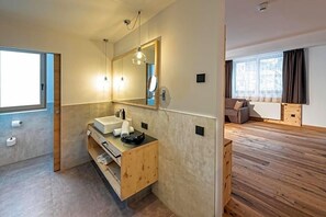 Un baño moderno con tocador de madera, un espejo grande y una ventana.