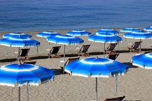 Una playa con varios sombrillas y sillas de playa azules.