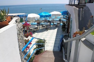 Una terraza con asientos al aire libre, una escalera y vistas al mar.