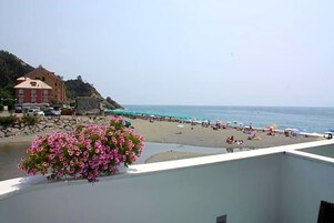 Una playa con gente, sombrillas y un edificio al fondo.