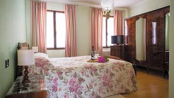 Ein Schlafzimmer mit Bett, Kommode, Spiegel und Fernseher.