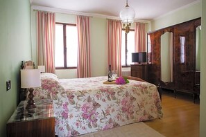 A bedroom with a bed, a dresser, a mirror, and a television.