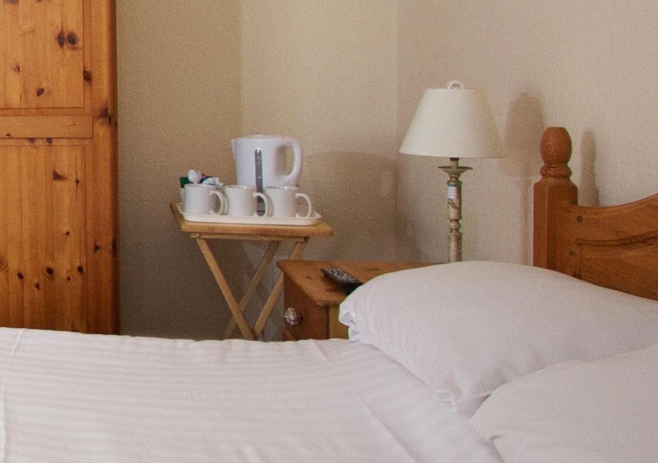 A hotel room with a wooden bed, a small bedside table with a lamp, and a nightstand with a remote control.