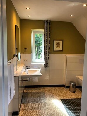 A bathroom with a window, a sink, a toilet, and a shower. - Hotel Anno 1848 (Lindern)