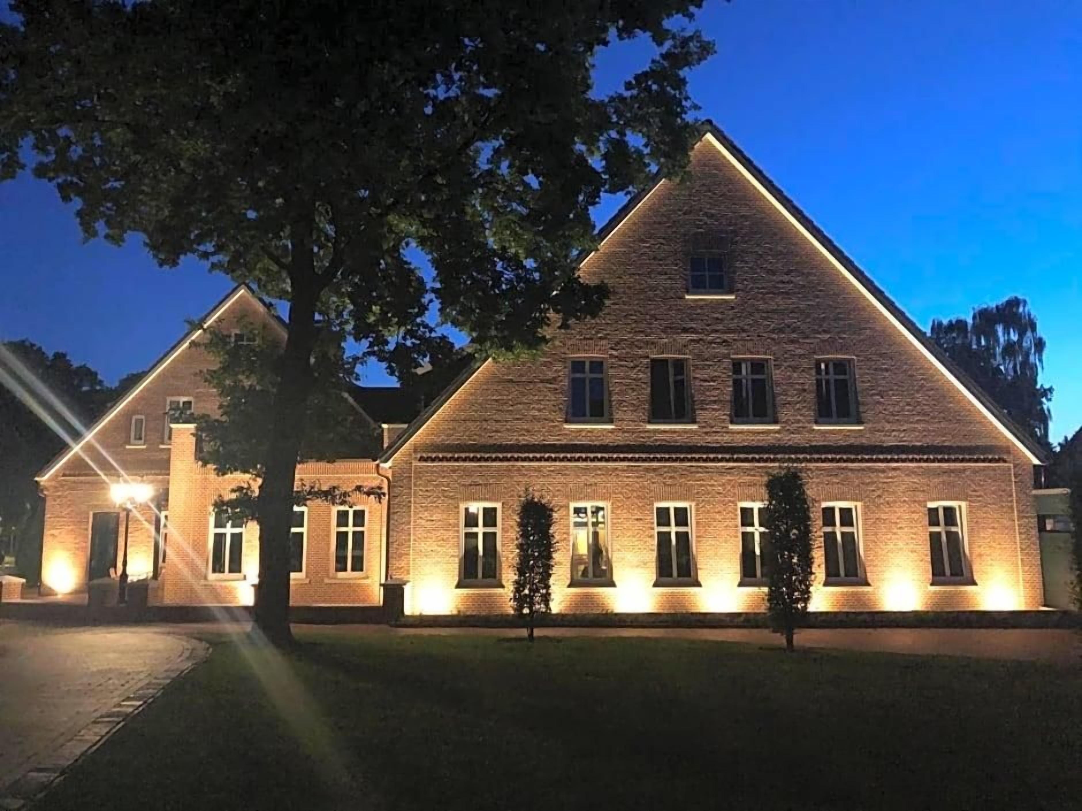 A large brick building with multiple windows and a well-lit entrance.