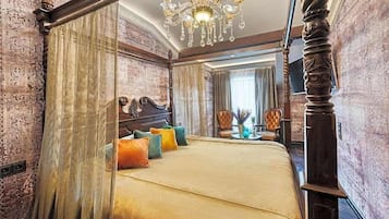 A four-poster bed with a canopy, a chandelier, and a view of a cityscape through a window.