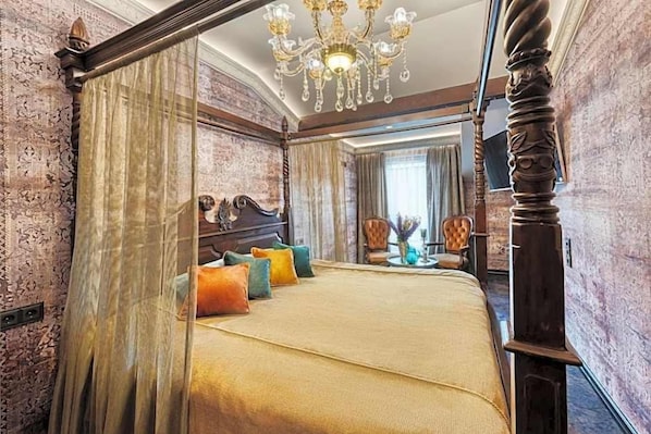 A four-poster bed with a canopy, a chandelier, and a view of a cityscape through a window.