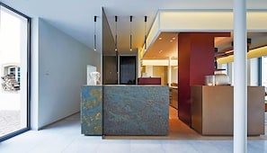 A modern interior with a reception desk, a large window, and a staircase leading to an upper level. - Weinhaus Henninger (Kallstadt)