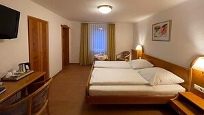A hotel room with a bed, bedside table, lamp, television, and a view of the corridor. - Hotel Württemberger Hof Garni (Rottenburg)