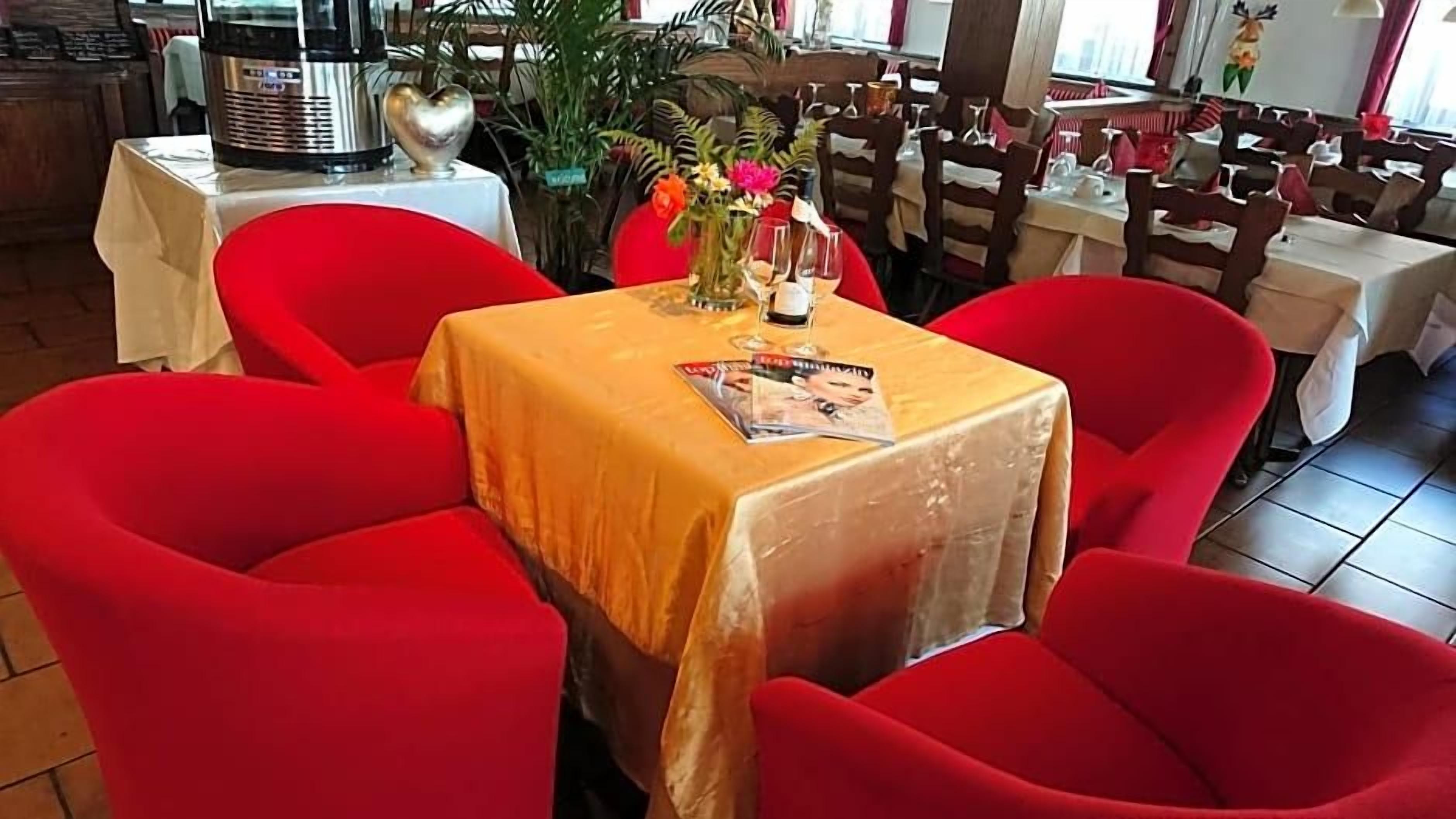 Un comedor con sillas rojas y una mesa cubierta con mantel amarillo.