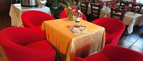 Un comedor con sillas rojas y una mesa cubierta con mantel amarillo.