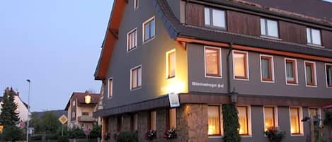 Un hotel con fachada de piedra, múltiples ventanas y un cartel que indica que es un 'Wirtshaus'.