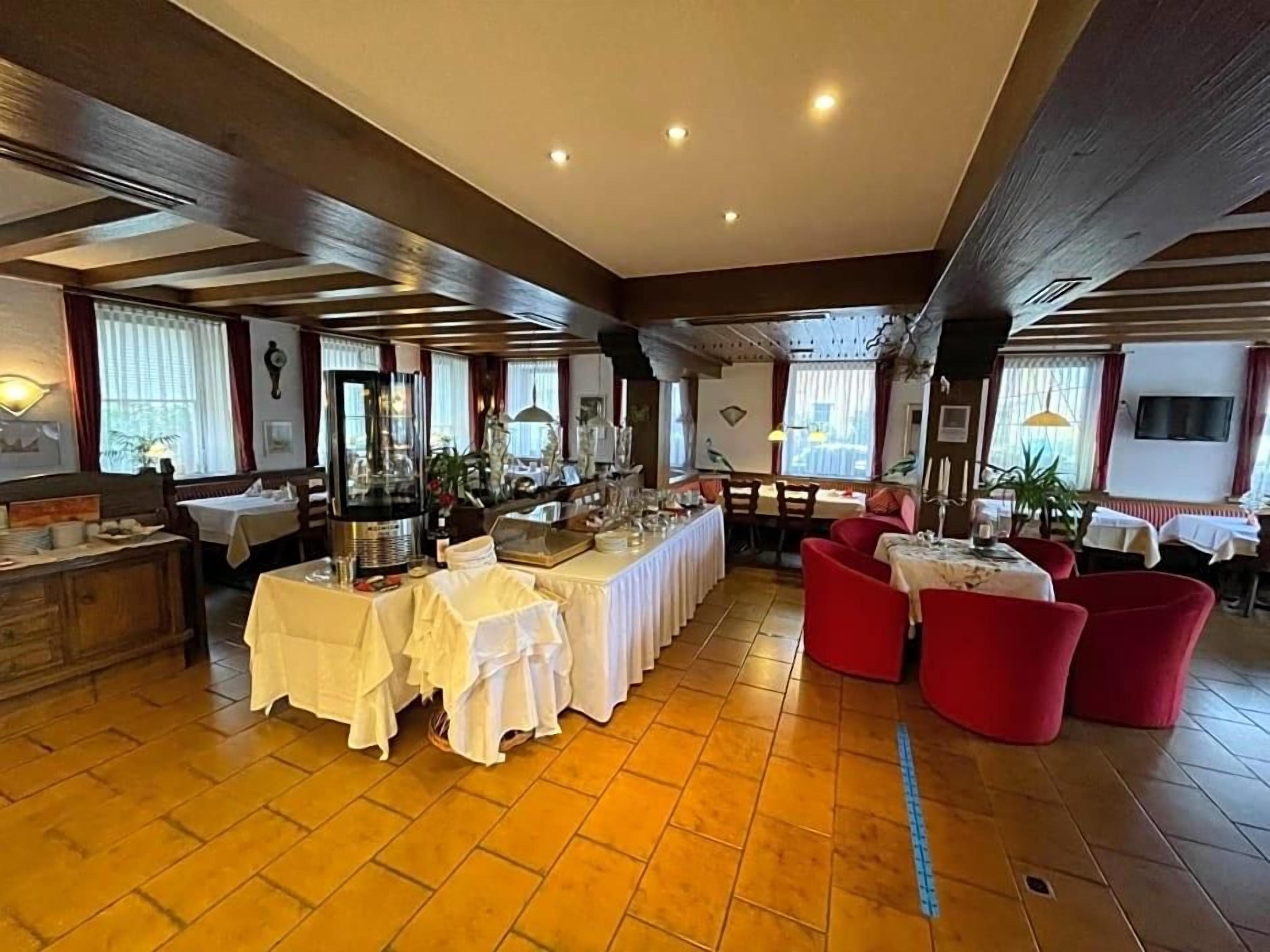 Un espace repas avec des tables dressées pour le service, un buffet et des sièges rouges.
