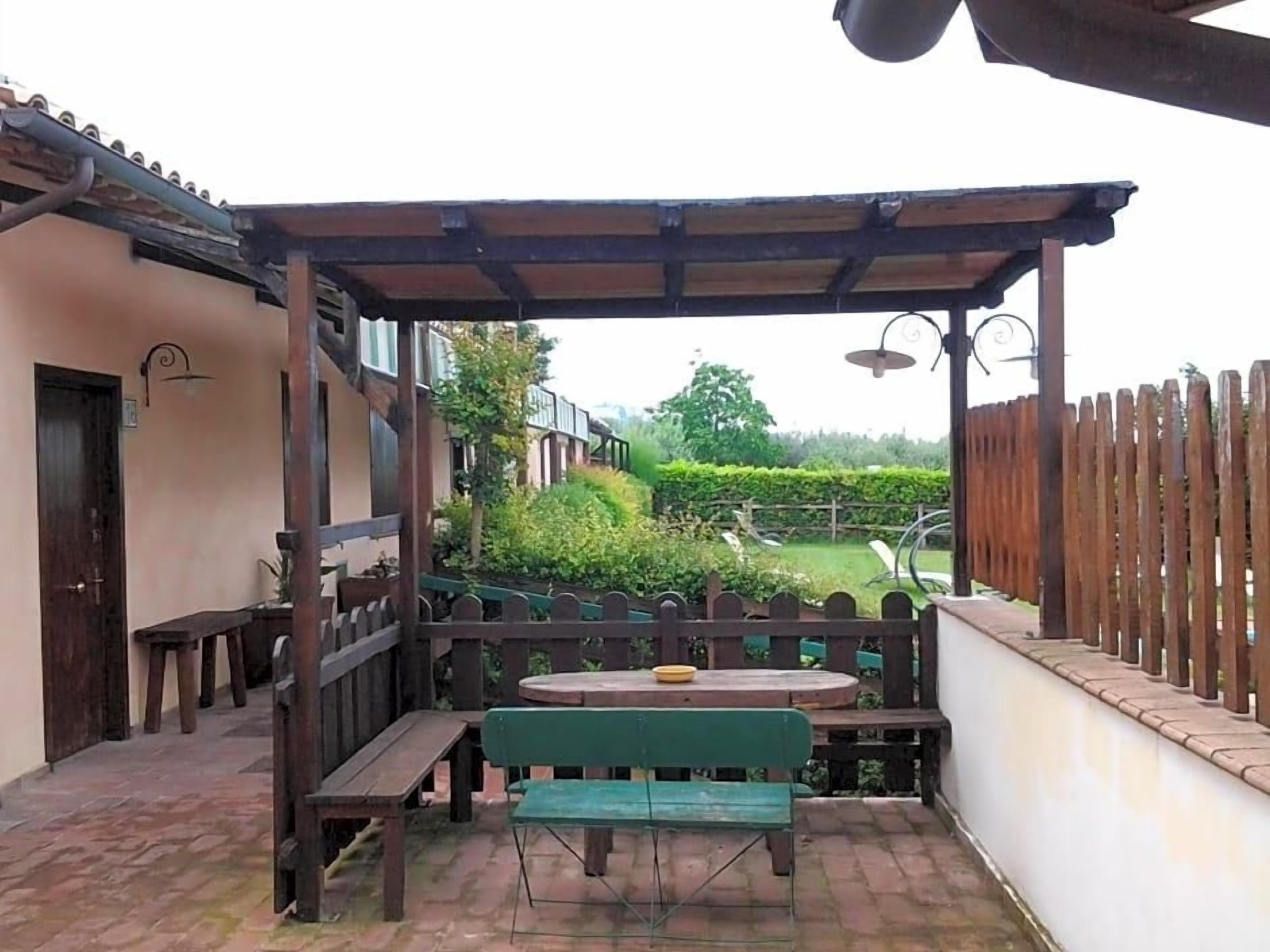 Eine Terrasse im Freien mit einer Holzbank, einem Tisch und einer Pergola.