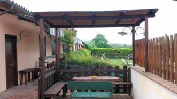 Eine Terrasse im Freien mit einer Holzbank, einem Tisch und einer Pergola.